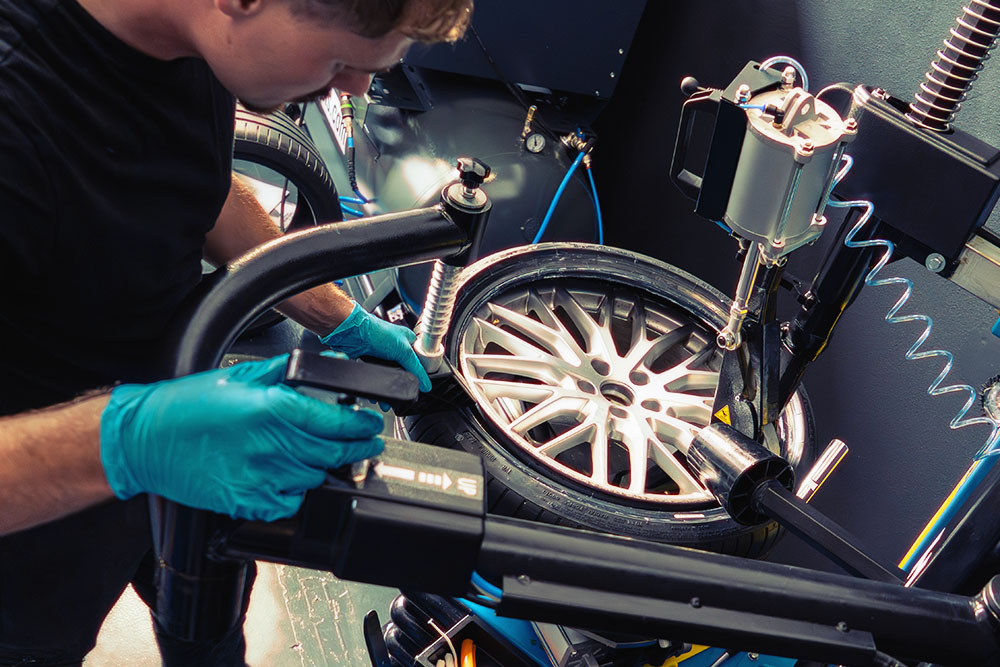 Monteur wisselt autoband met moderne apparatuur in autogarage Valkenswaard – DLF Automotive onderhoud en bandenservice.